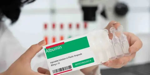 Ręce trzymają opakowanie z napisem "Albumin". To zastrzyk, który może pomóc w leczeniu.