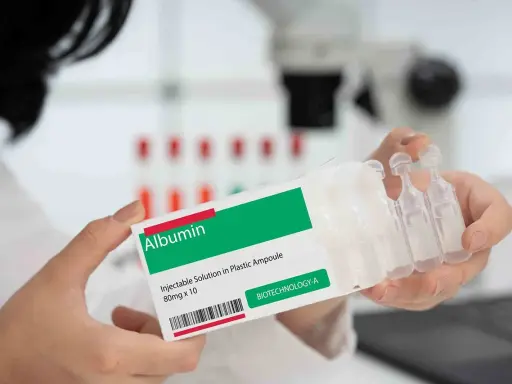 Ręce trzymają opakowanie z napisem "Albumin". To zastrzyk, który może pomóc w leczeniu.