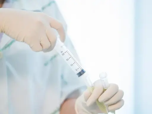 Ręce w rękawiczkach przygotowują pobranie płynu mózgowo rdzeniowego do analizy.